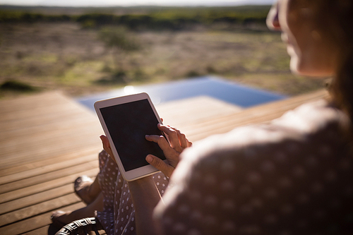 Rear view of senior woman using digital tablet while sitting