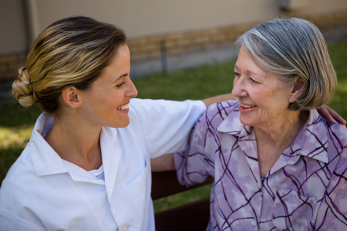 High angle view of senior woman talking to doctor while sitting on bench in yard