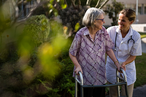 Doctor talking to woman while assisting her in walking at yard