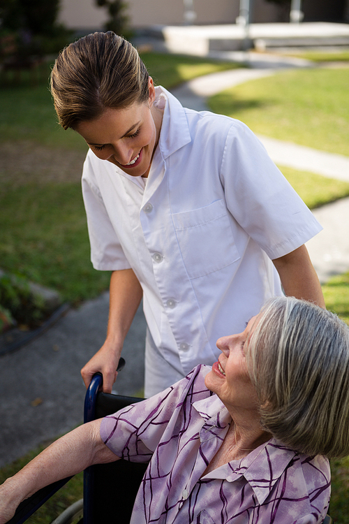 smiling doctor talking to senior woman sitting on . at park