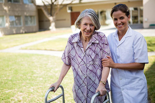 Portrait of doctor helping senior woman in walking at park