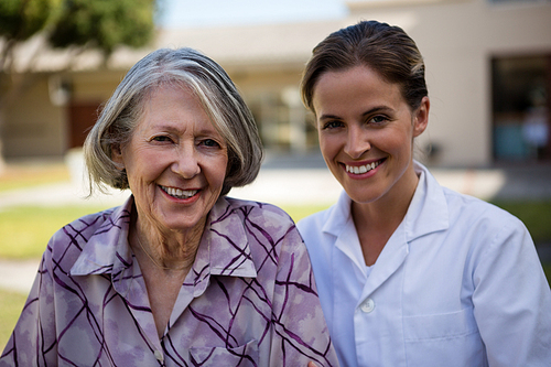 Portrait of smiling doctor and senior woman standing at park