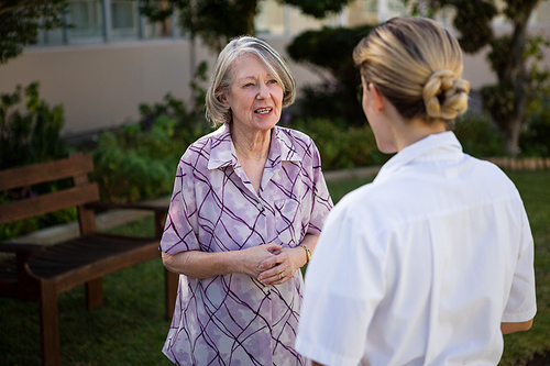 Senior woman and doctor talking while standing in park