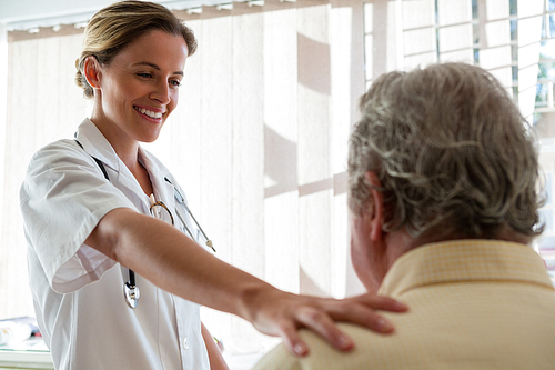 Female doctor talking to senior man in retirement home