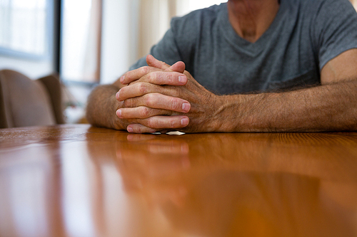Midsection of senior man sitting at table in nursing home