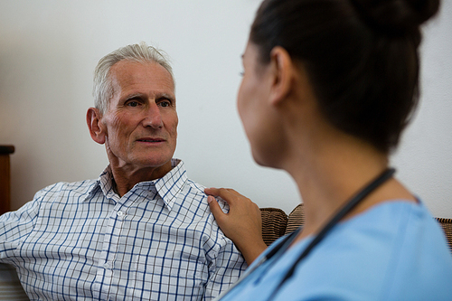 Female doctor consoling senior man in nursing home