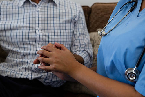 Midsection of female doctor consoling senior man in nursing home