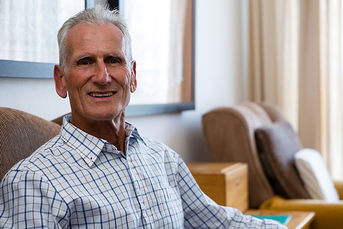 Portrait of smiling senior man relaxing on armchair in nursing home