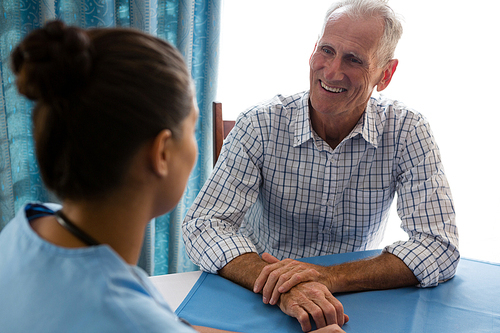 Senior man interacting with female doctor at table in retirement home