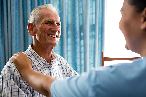 Happy senior man talking to female doctor in retirement home