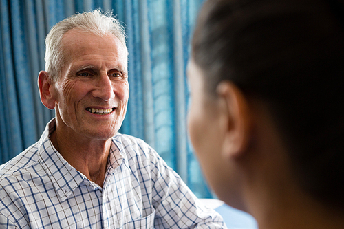 Happy senior man interactin with female doctor in retirement home