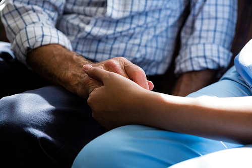 Midsection of female doctor consoling senior man in retirement home