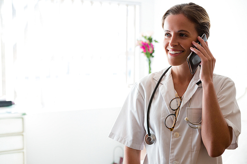 Smiling female doctor talking on mobile phone in nursing home