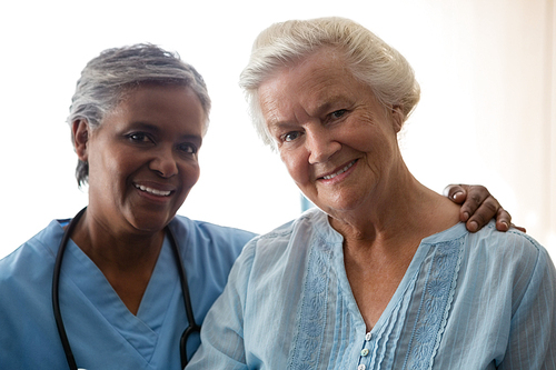 Portrait of smiling nurse and senior woman standing in nursing home