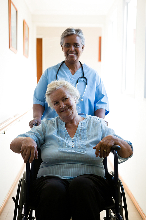 portrait of nurse pushing patient sitting in . at retirement home