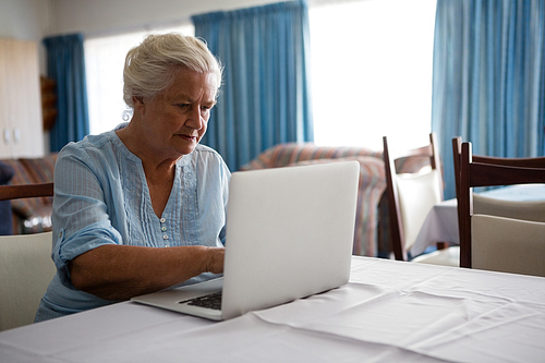 Senior woman using laptop while sitting at table in nursing home