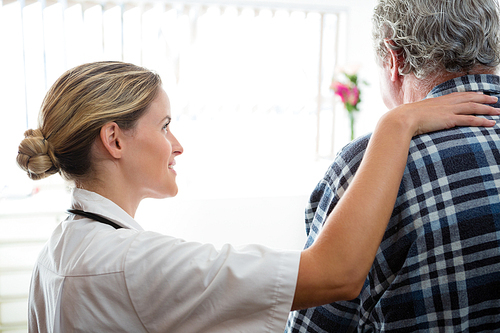 Side view of female doctor consoling senior man in retirement home