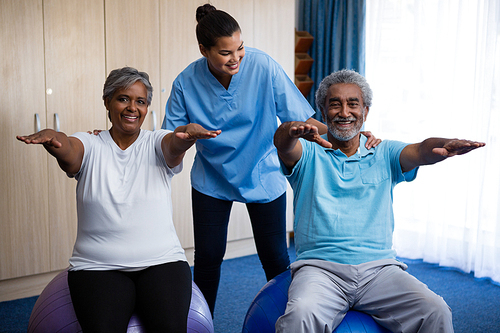 Nurse guiding seniors in exercising at retirement home