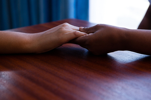 Cropped hands of nurse consoling senior woman at table in retirement home