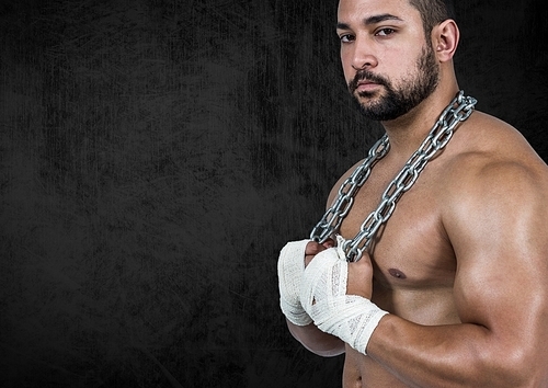 Determined muscular man holding chains against black background