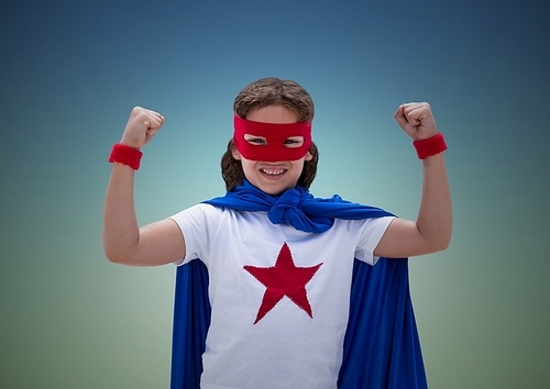 Happy boy in superhero costume showing fists against blue background
