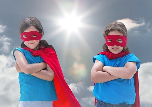 Digital composition of kids in superhero costumes standing with arms crossed against sky in background