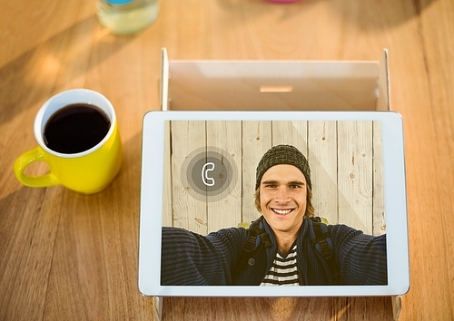 Digital tablet displaying man on video calling screen on wooden table