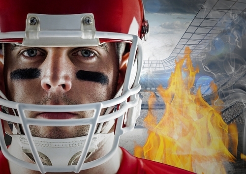 Digital composition of american football player with flames and stadium in background
