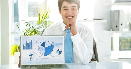 Businessman with laptop displaying graph charts on screen at office