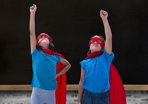 Digital composition of girls in superhero costume pointing upwards against blackboard in background