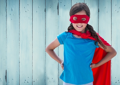 Digital composition of girl in superhero costume with hands on her hip standing against against wooden background