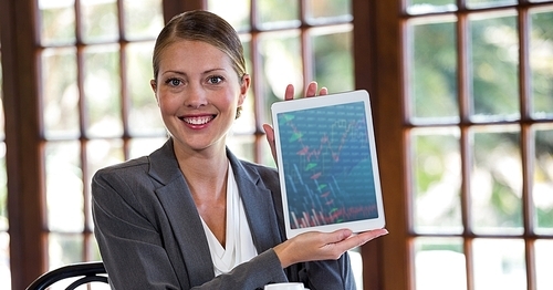 Portrait of woman holding digital tablet against window in background