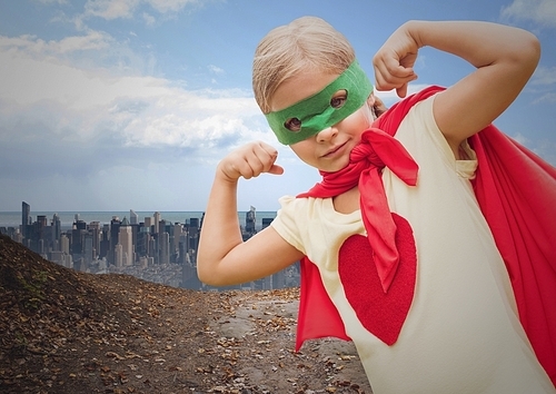 Digital composition of girl in superhero costume flexing her arms against cityscape