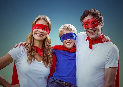 Portrait of father, mother and son in superhero costume standing against green background