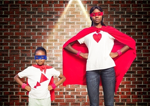 Portrait of super woman and girl in red cape against brick wall