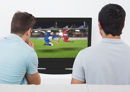 Rear view of men watching football match on television at home