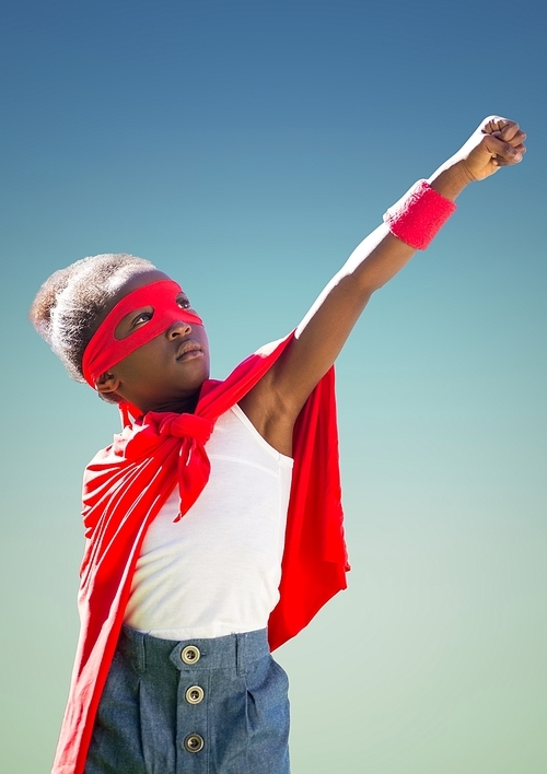 Kid in red cape and mask standing with fist against turquoise background