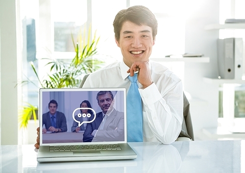 Portrait of smiling businessman showing laptop with video calling screen in office