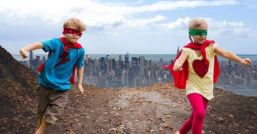 Digital composite of happy kids wearing red cape and mask having fun against cityscape