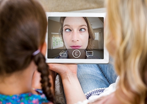 Mother and daughter having video calling in lving room at home
