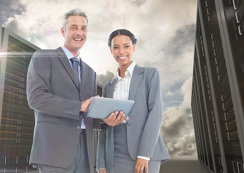 Digital composite of smiling businesspeople using digital tablet against server background