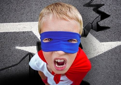 Digital composite of aggressive super boy in red cape and blue mask on road