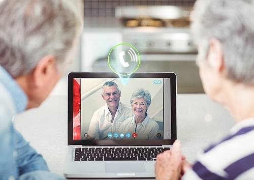 Senior couple having video call with friends on laptop at home