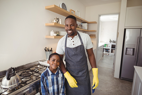 Portrait of smiling father and son standing together in kitchen