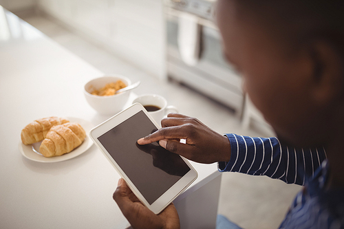 Man using a digital tablet in kitchen at home