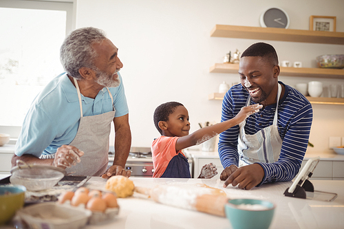 Smiling multi-generation family with flour on the nose standing in the kitchen