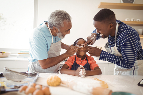 Smiling multi-generation family with flour on the nose standing in the kitchen