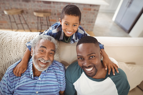 Portrait of smiling multi-generation family sitting together on sofa in living room