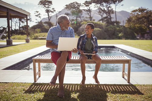 Grandfather and grandson interacting with each other near swimming pool on a sunny day