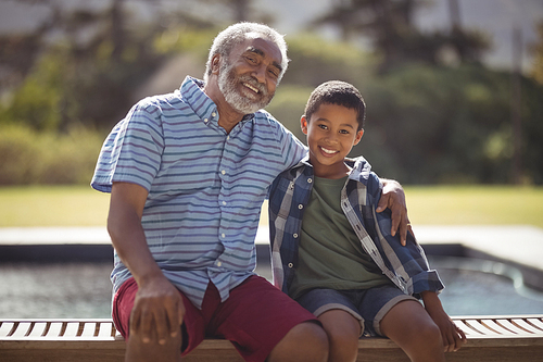 Portrait of smiling grandfather and grandson sitting together on bench